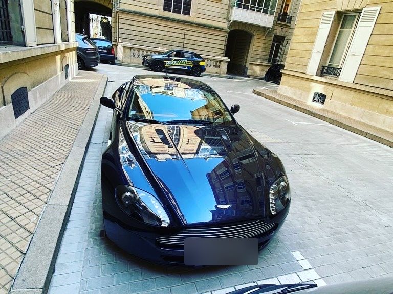 Aston Martin bleu nuit lustrée, reflets miroir sur le capot après polish